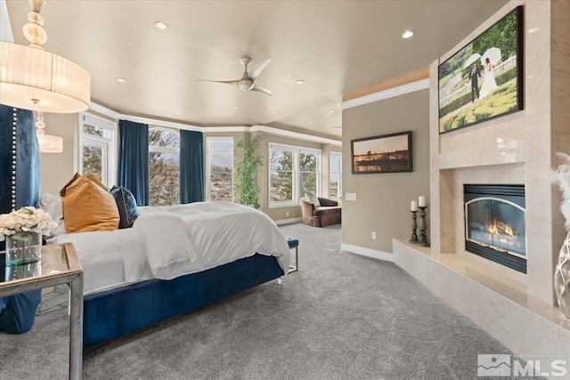 carpeted bedroom with ceiling fan, ornamental molding, and a premium fireplace