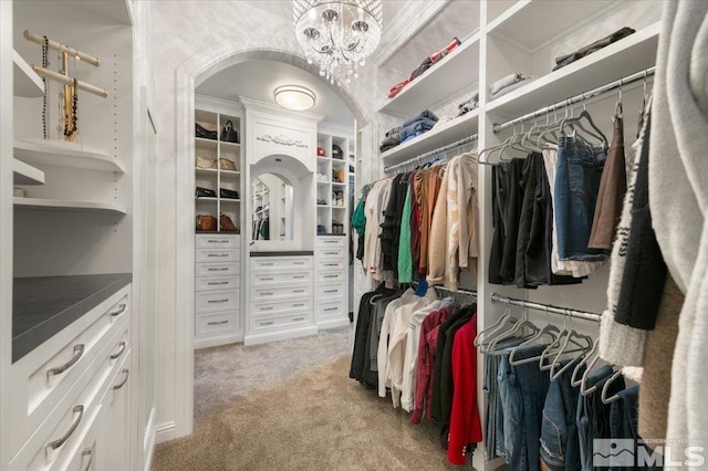 walk in closet with light carpet and a chandelier