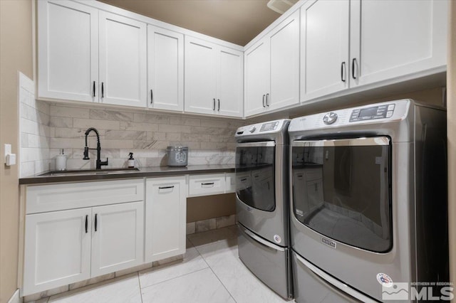 laundry area featuring sink, light tile patterned floors, cabinets, and independent washer and dryer