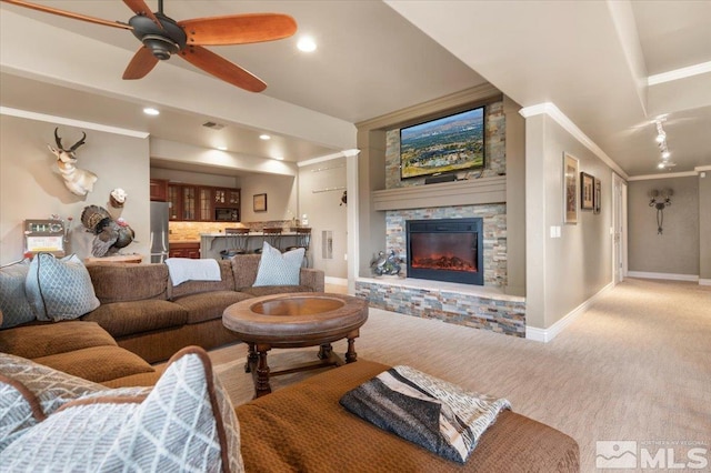 carpeted living room featuring crown molding, a fireplace, and ceiling fan