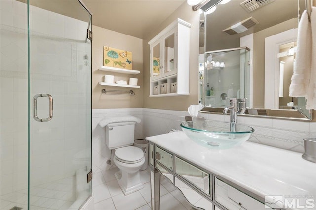 bathroom featuring tile patterned floors, walk in shower, vanity, tile walls, and toilet