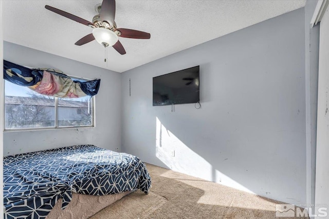 bedroom featuring carpet, ceiling fan, and a textured ceiling