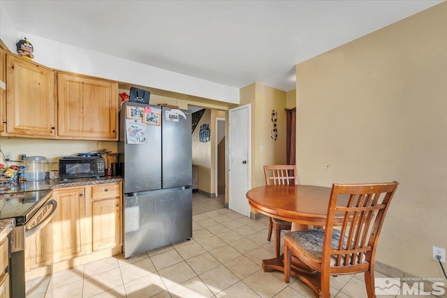 kitchen with light brown cabinetry, light tile patterned floors, and appliances with stainless steel finishes