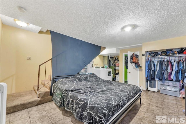 tiled bedroom with washer and dryer, a textured ceiling, and a closet