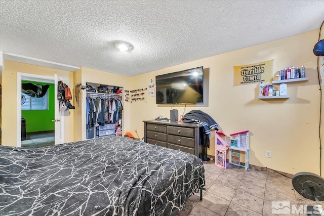 tiled bedroom with a textured ceiling and a closet