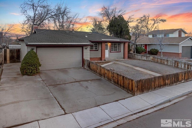 ranch-style home with roof with shingles, fence, driveway, and an attached garage