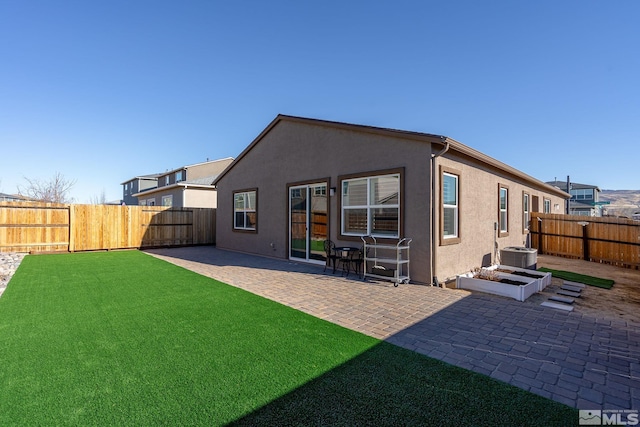 back of house with a lawn and a patio