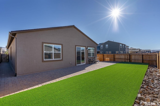 back of property with a lawn and a patio