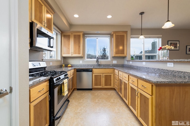 kitchen featuring dark stone counters, hanging light fixtures, stainless steel appliances, and sink