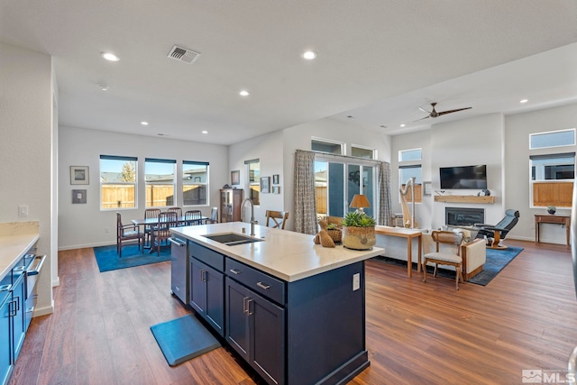 kitchen featuring a kitchen island with sink, sink, stainless steel dishwasher, dark hardwood / wood-style floors, and ceiling fan