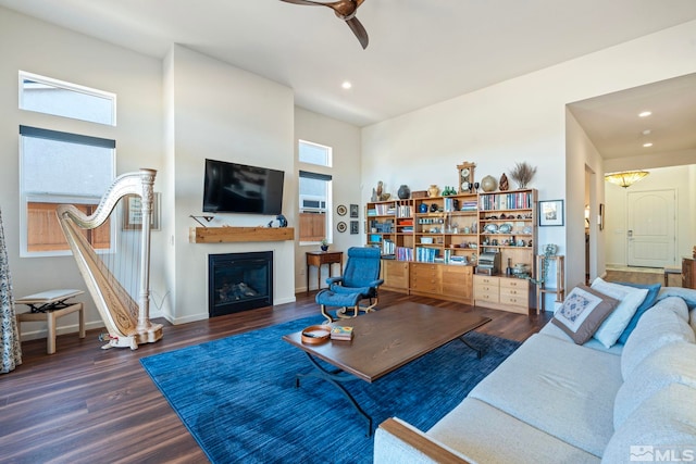 living room with ceiling fan, dark wood-type flooring, and a high ceiling