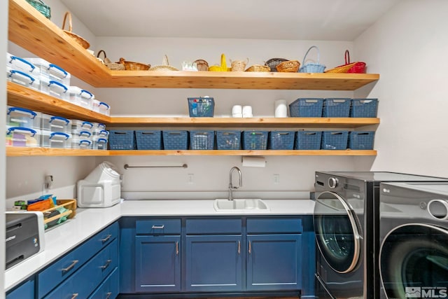 laundry room featuring washing machine and clothes dryer, cabinets, and sink