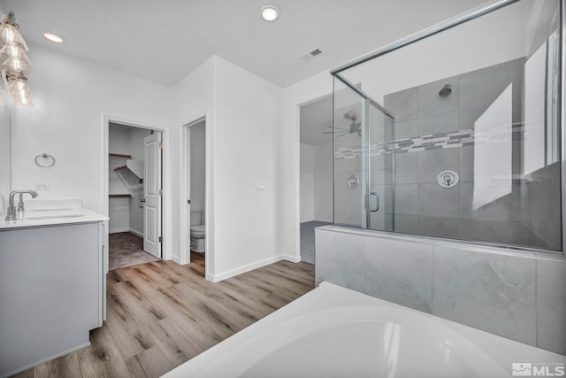 full bathroom featuring vanity, plus walk in shower, wood-type flooring, and toilet