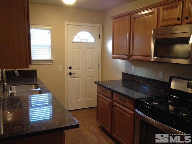 kitchen with black gas range, dark stone countertops, sink, and dark wood-type flooring