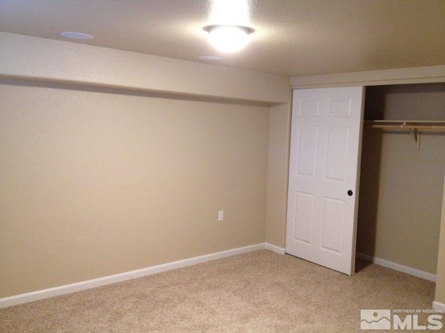 unfurnished bedroom with a closet and light colored carpet