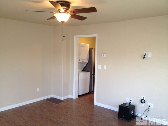 unfurnished room with dark hardwood / wood-style flooring, stacked washing maching and dryer, and ceiling fan