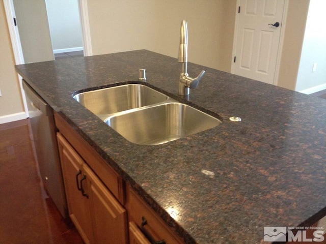 kitchen featuring dishwasher, sink, and dark stone counters