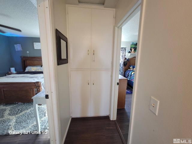 hallway with dark hardwood / wood-style floors and a textured ceiling