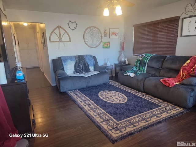 living room featuring ceiling fan and dark wood-type flooring