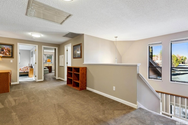 corridor with carpet floors and a textured ceiling