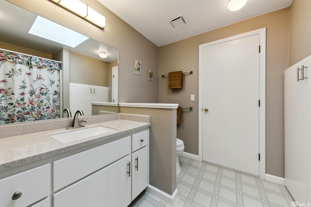 bathroom featuring vanity, toilet, and a skylight