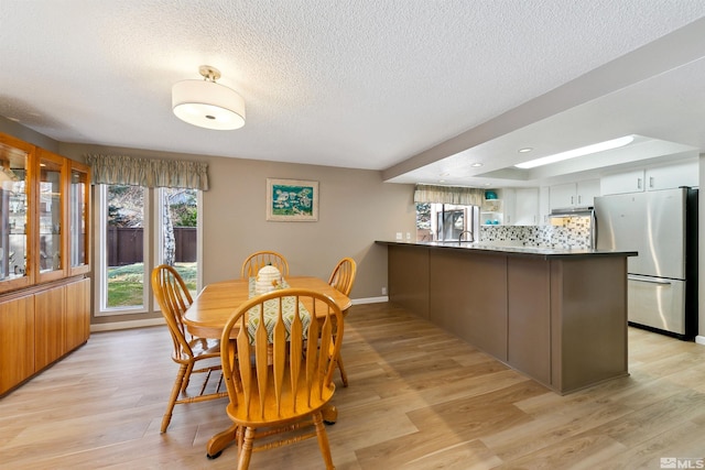 dining space with a textured ceiling and light hardwood / wood-style floors