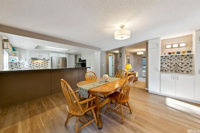 dining room featuring a textured ceiling and light hardwood / wood-style floors