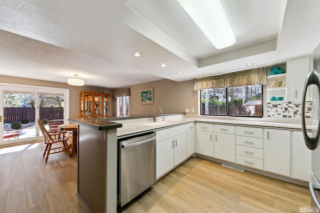 kitchen featuring kitchen peninsula, stainless steel appliances, a healthy amount of sunlight, sink, and white cabinetry