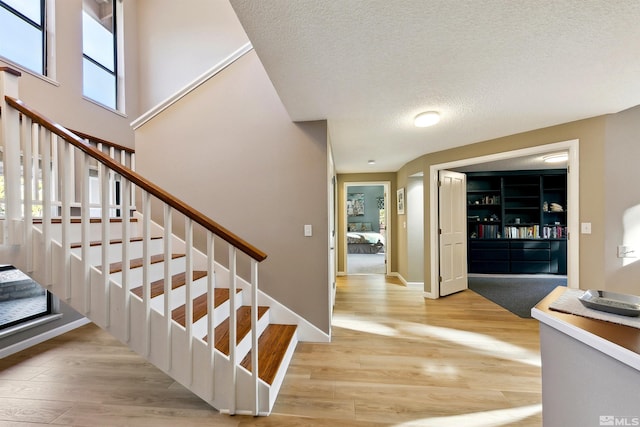 stairs with hardwood / wood-style floors and a textured ceiling