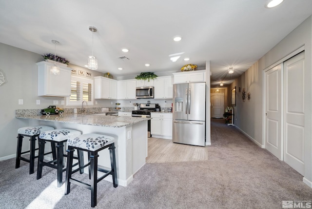 kitchen with sink, hanging light fixtures, white cabinetry, kitchen peninsula, and stainless steel appliances