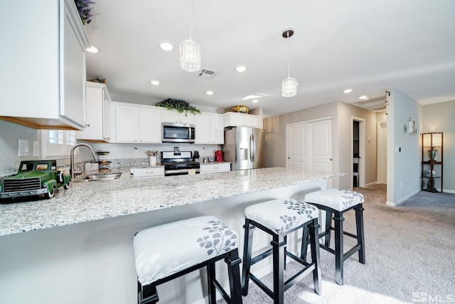 kitchen featuring a breakfast bar, stainless steel appliances, sink, white cabinets, and hanging light fixtures