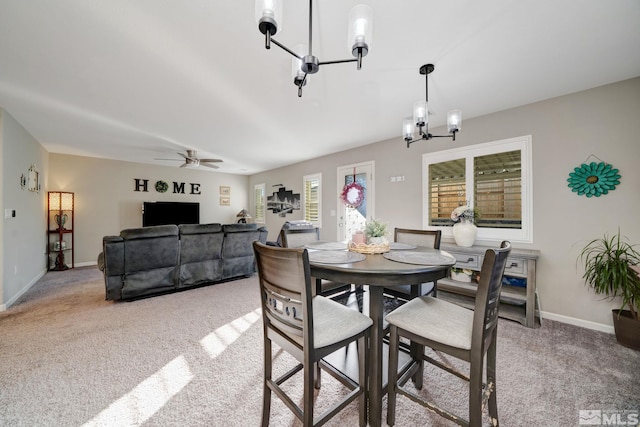 carpeted dining area featuring ceiling fan with notable chandelier