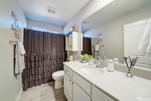 bathroom featuring walk in shower, vanity, wood-type flooring, and toilet