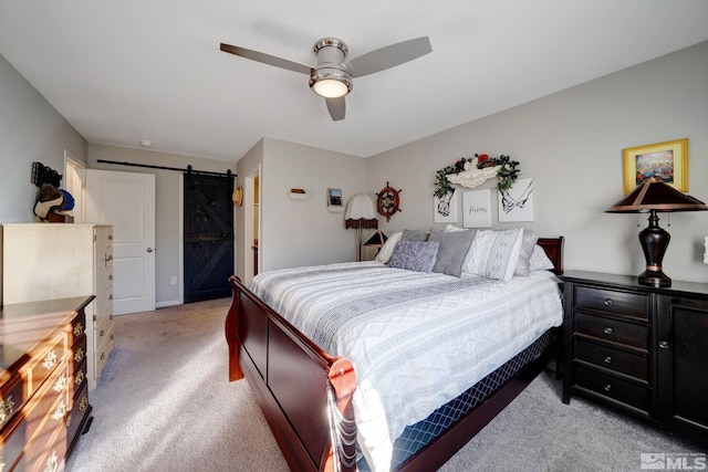 carpeted bedroom featuring a barn door and ceiling fan