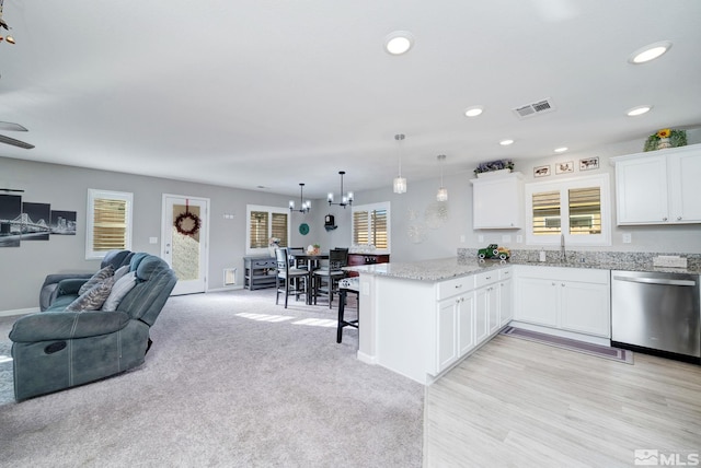 kitchen featuring white cabinets, sink, hanging light fixtures, stainless steel dishwasher, and kitchen peninsula