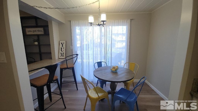 dining room featuring wood-type flooring, ornamental molding, and a chandelier