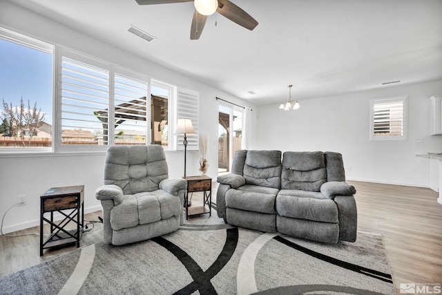 living room featuring hardwood / wood-style floors, ceiling fan with notable chandelier, and a healthy amount of sunlight