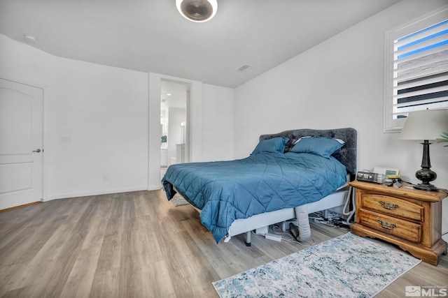 bedroom with ensuite bath and light hardwood / wood-style flooring