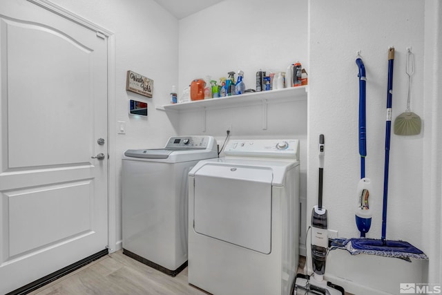 laundry area with washer and clothes dryer and light hardwood / wood-style flooring