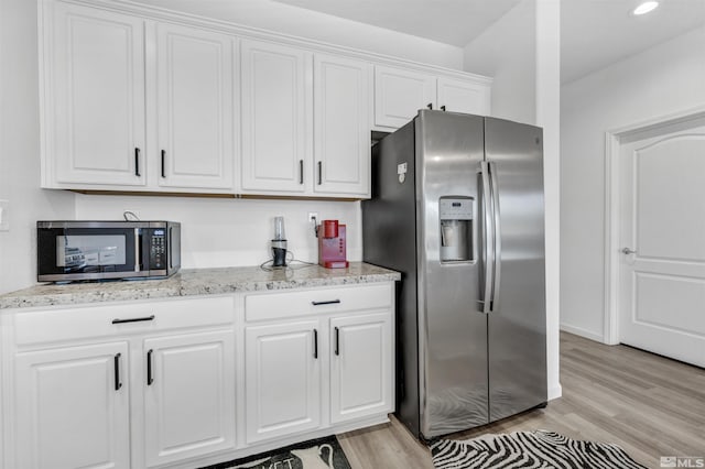 kitchen featuring light stone countertops, white cabinetry, appliances with stainless steel finishes, and light hardwood / wood-style flooring