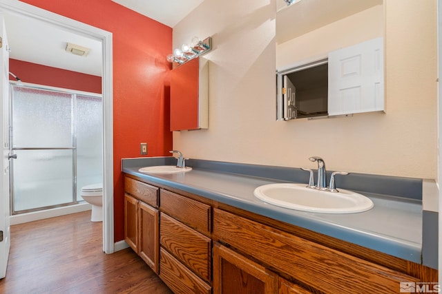 bathroom featuring an enclosed shower, vanity, toilet, and wood-type flooring