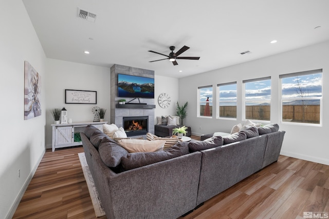 living room featuring a fireplace, hardwood / wood-style floors, and ceiling fan