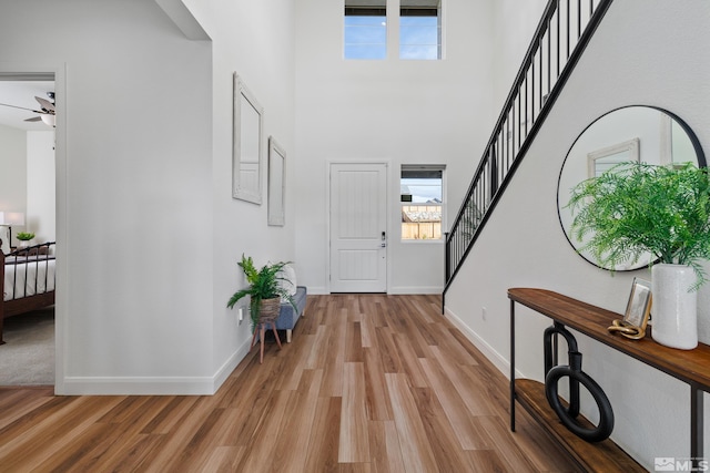 entrance foyer with ceiling fan, light wood-type flooring, and a high ceiling