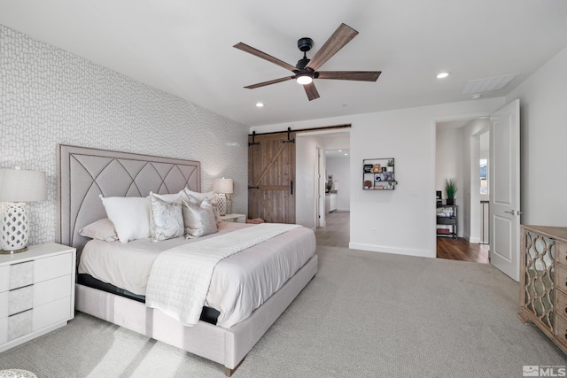 carpeted bedroom featuring a barn door and ceiling fan