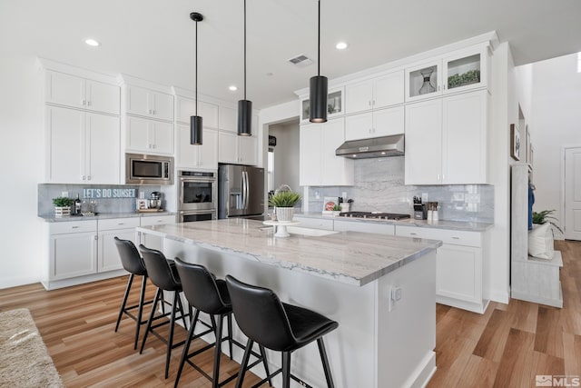 kitchen featuring appliances with stainless steel finishes, a center island, decorative light fixtures, and white cabinetry