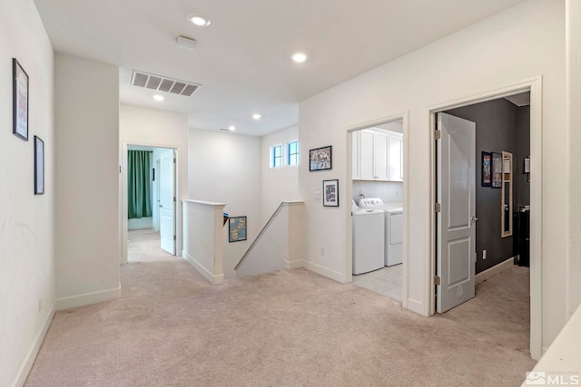 hall with independent washer and dryer and light carpet