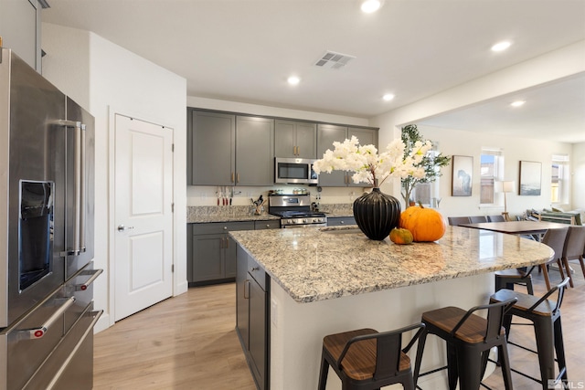 kitchen featuring gray cabinetry, light stone counters, a center island, and stainless steel appliances