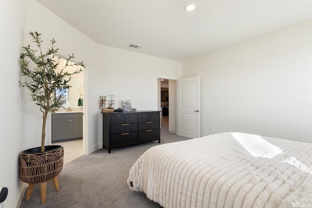 bedroom featuring ensuite bathroom and light colored carpet