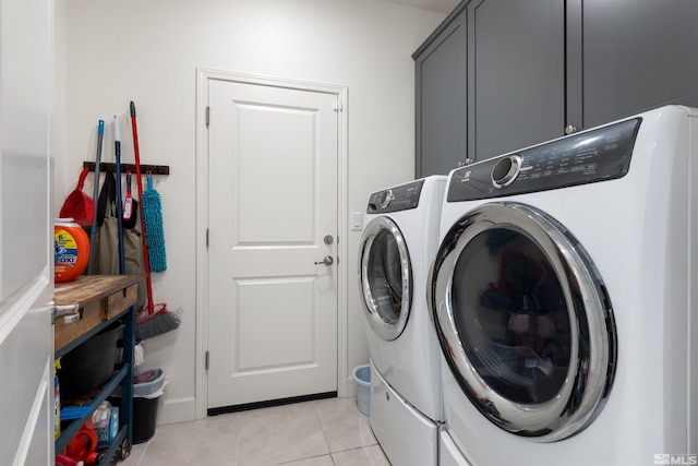 laundry room with cabinets, light tile patterned floors, and washing machine and clothes dryer