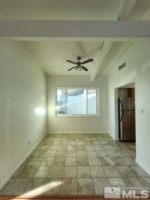 spare room featuring a ceiling fan, visible vents, lofted ceiling with beams, and baseboards